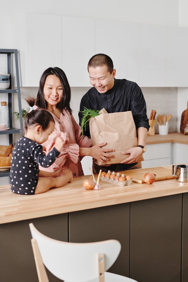 Smiling family with child preparing food together in modern kitchen.